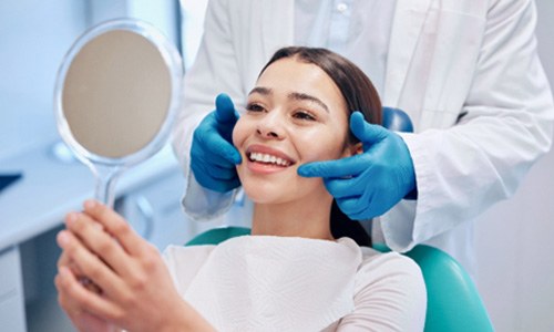 Woman smiling at reflection in her dentist's mirror