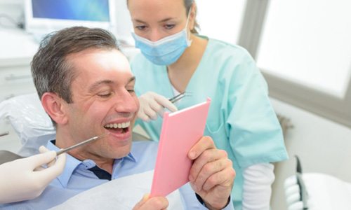 man looking at his dental crown in a mirror