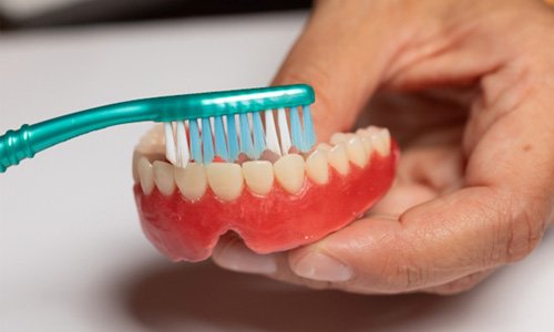 Man brushing dentures