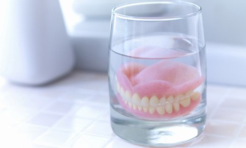 Dentures soaking in a glass