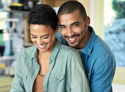 Smiling man holding smiling woman from behind