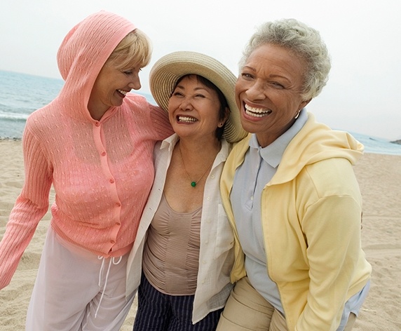 Three older women laughing at beach