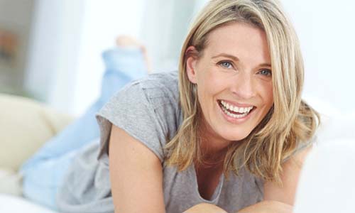 Older woman smiling on a couch while using laptop