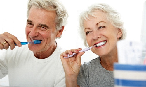 couple brushing teeth in bathroom