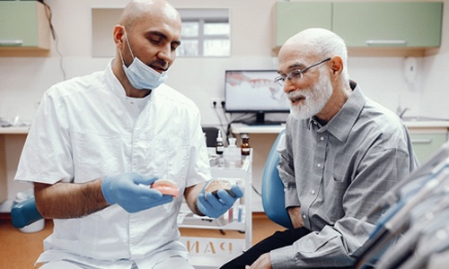 An older man listening as his dentist explains whether he is a qualified candidate for dental implants in Big Pine Key