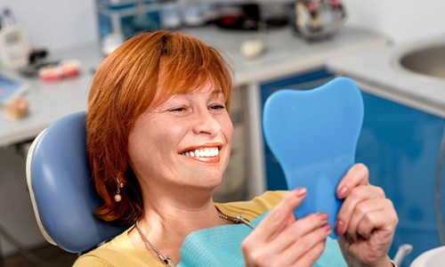 A middle-aged woman with red hair admiring her new smile while at the dentist’s office in Big Pine Key