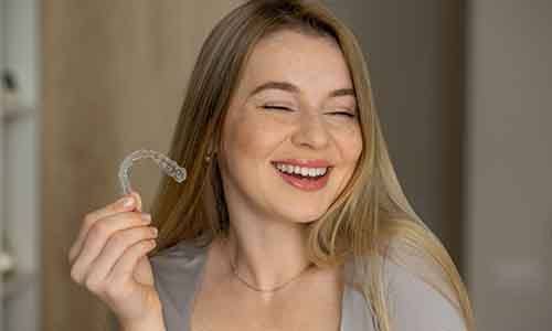 Woman with grey shirt holding Invisalign aligner