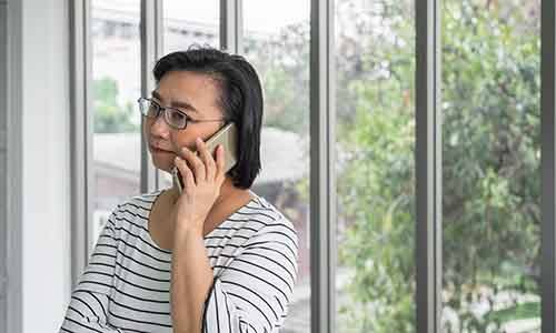 Concerned woman in striped shirt talking on phone