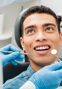 Young man in dental chair smiling at dentist before exam