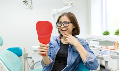 Woman smiling in mirror at dental office