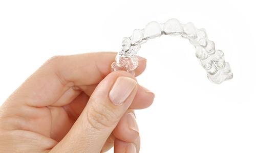 Hand holding an Invisalign tray