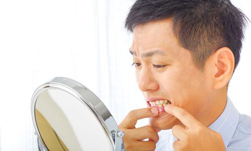Concerned man examining his gums in the mirror