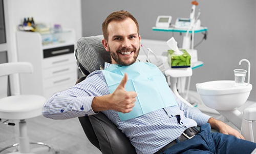 Man in dental chair giving thumbs up