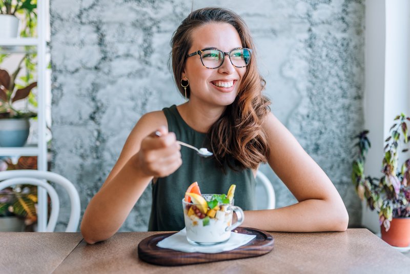 Woman smiling while eating fruit salad