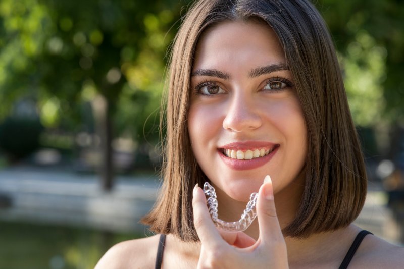 Young woman holding her Invisalign aligner