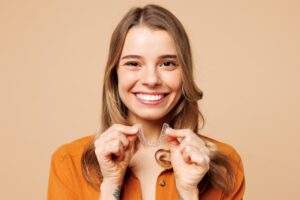 Young woman holding clear aligner.