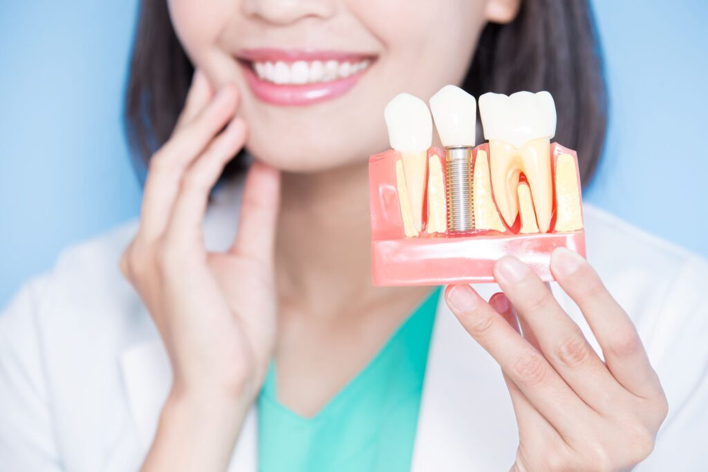 Chin-to-chest view of woman in white coat holding sample implant and touching cheek